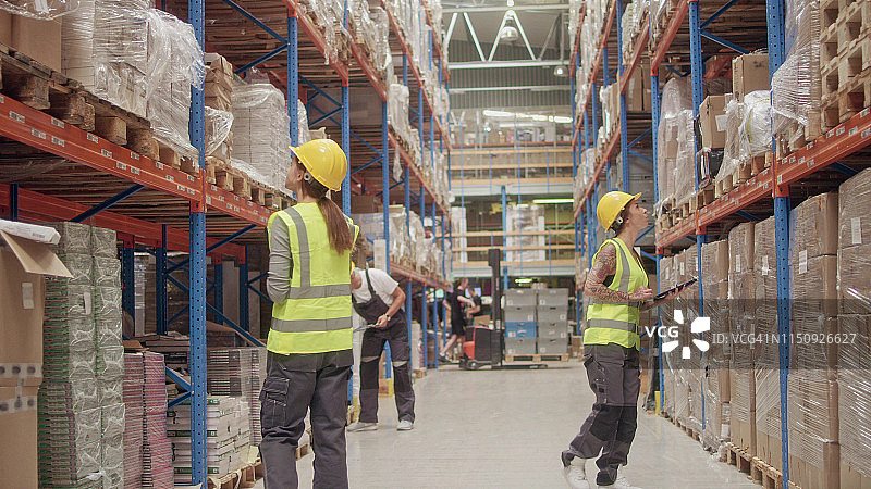 在仓库检查库存并进行商务电话的团队图片素材