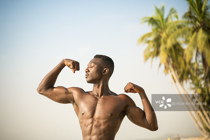 男子在海滩上展示手臂肌肉图片素材