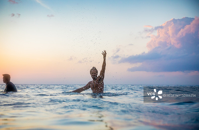 男人在菲律宾伊罗戈省帕古德普德的日落时分在海中嬉戏图片素材