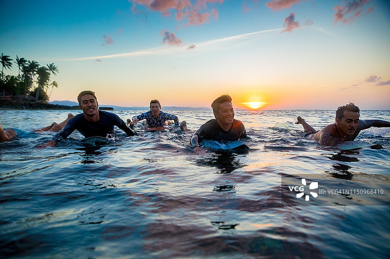 日落时分在菲律宾伊罗戈 Norte Pagudpud 海中滑行的冲浪者图片素材