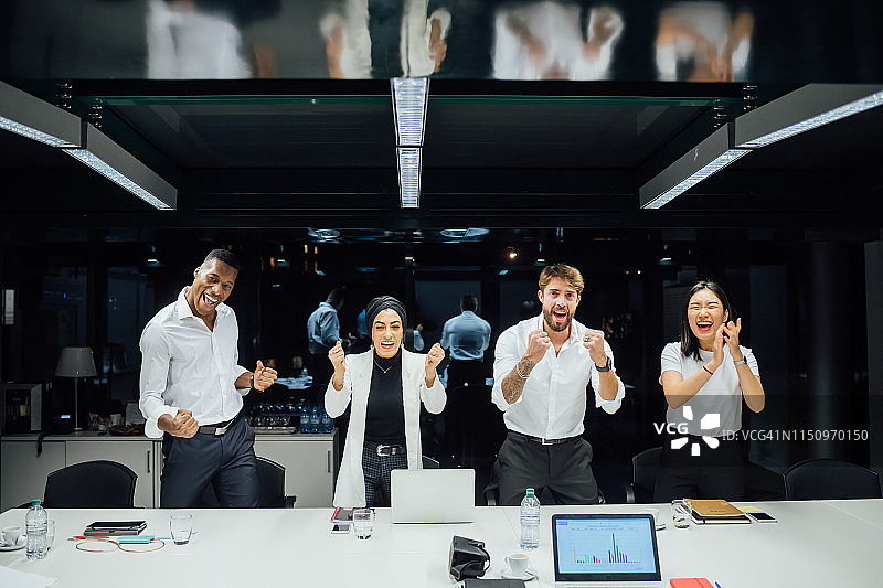 自信的商务团队在会议桌旁庆祝会议，肖像图片素材