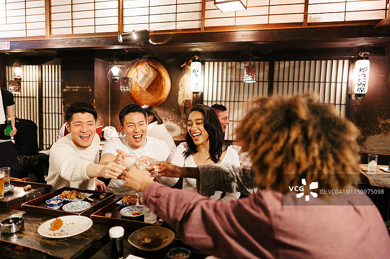 混合种族旅行者在日式酒吧喝酒图片素材