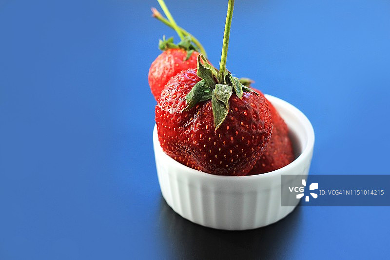 深色背景下陶瓷碗里的新鲜红色草莓图片素材