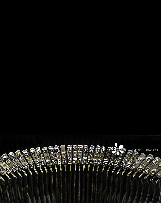 黑色背景上的旧式打字机和钥匙，留有文案空间图片素材