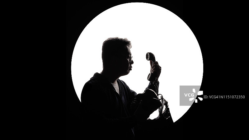 中国中年男子看着老式座机电话剪影图片素材