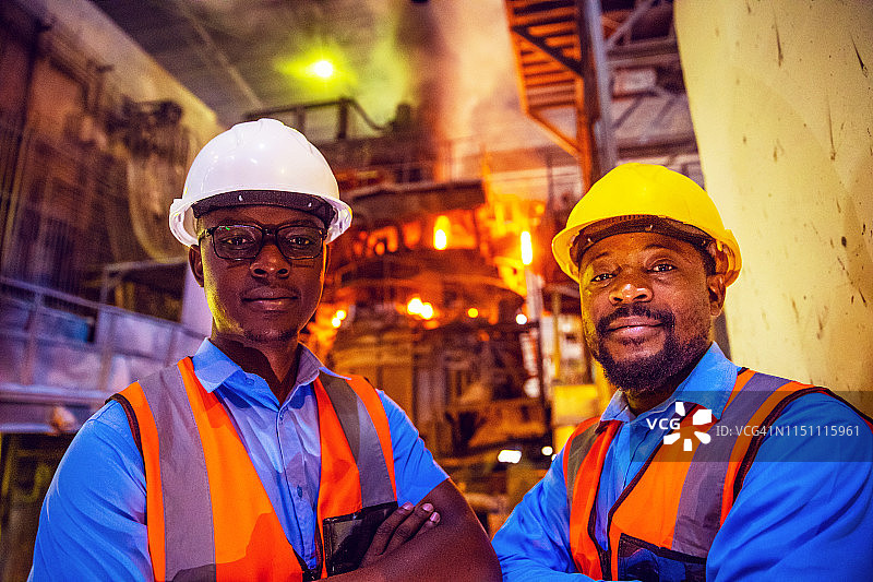 站在电弧炉旁的非洲钢铁厂工人肖像图片素材