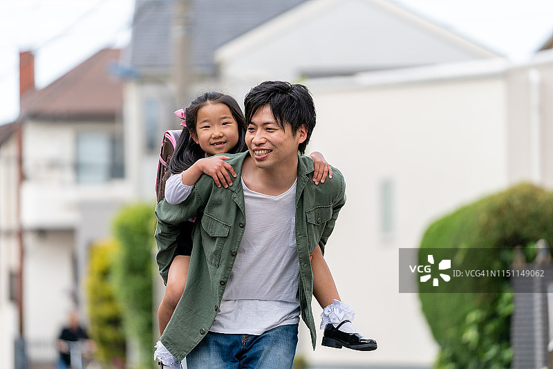 年轻的父亲在户外背着女儿图片素材