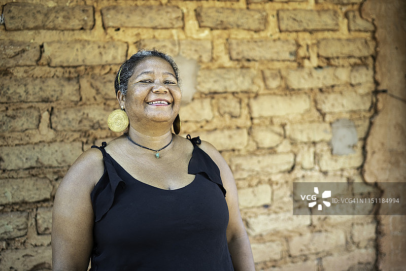 在土坯房前的一位中年妇女肖像图片素材