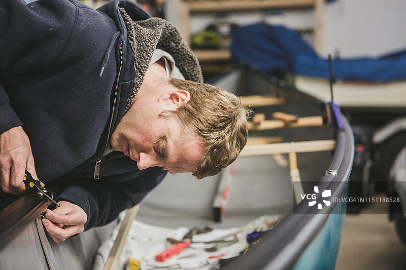 男人用螺丝刀修理独木舟图片素材