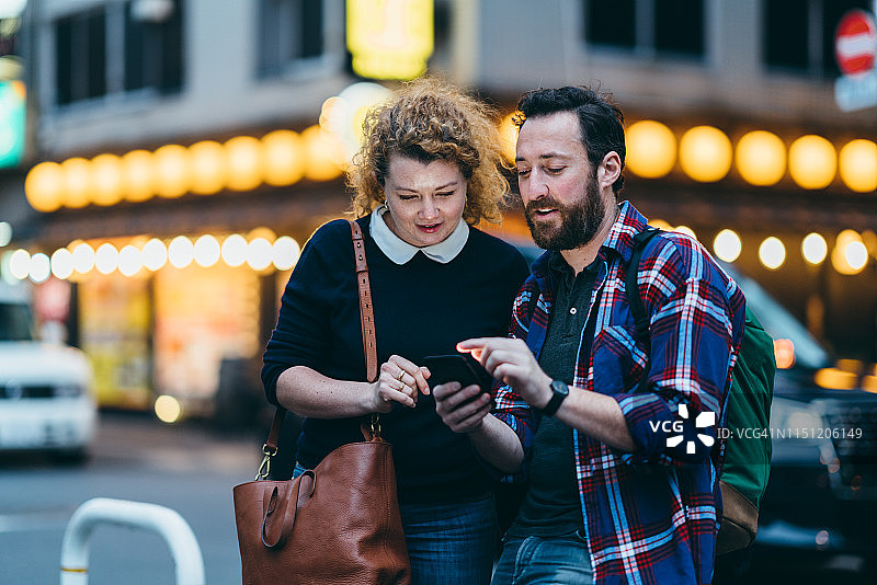 情侣旅行者在城市里用智能手机查找方向图片素材