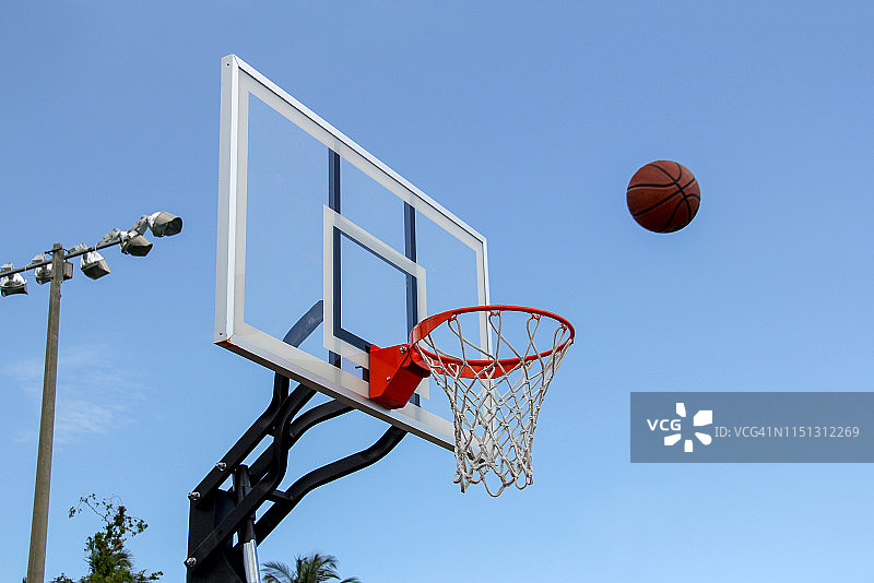 户外篮球场半空中的篮球与篮筐图片素材