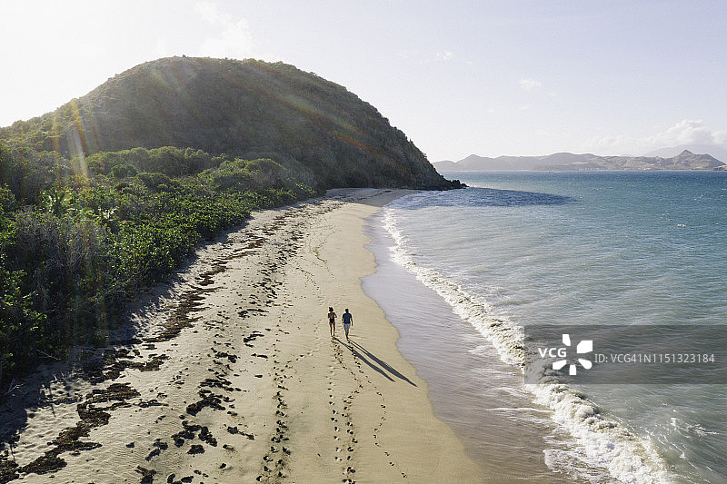 情侣在沙滩漫步的航拍视角图片素材