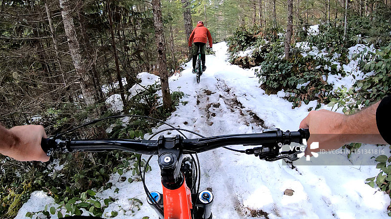 山地自行车骑手在雪地小径上的第一视角图片素材