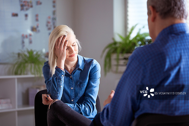 沮丧的年轻女子与治疗师交谈图片素材