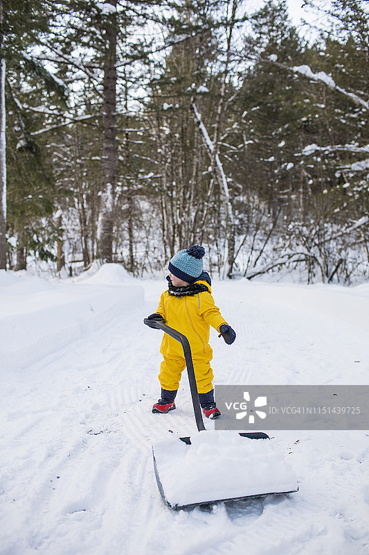 幼儿用大雪铲清理车道上的积雪图片素材