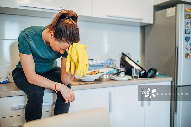 女人坐在厨房台面上，戴着防护手套图片素材