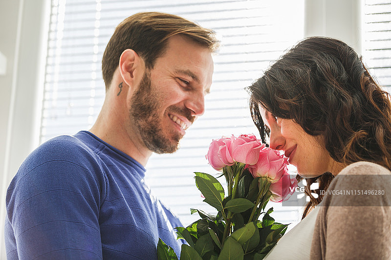 微笑的男人给妻子送玫瑰花束图片素材