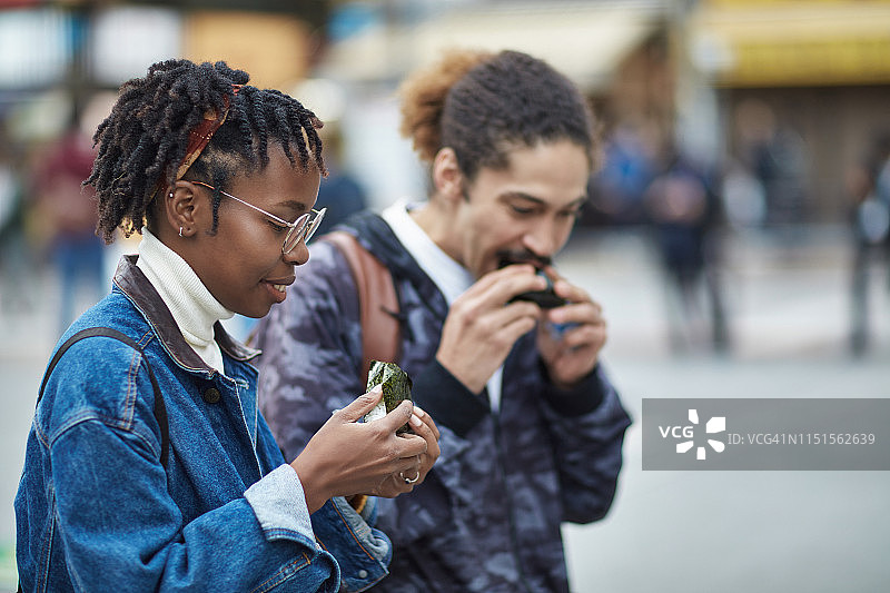 在城市里吃饭团的男女朋友图片素材