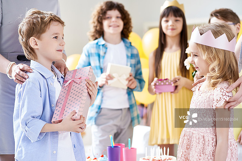 迷人的男孩在聚会上给女孩送礼物图片素材