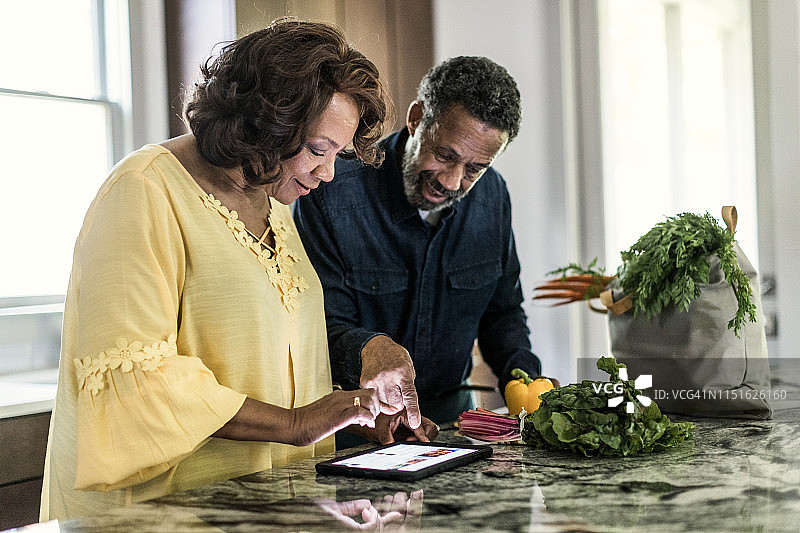 老年夫妇在厨房使用平板电脑图片素材