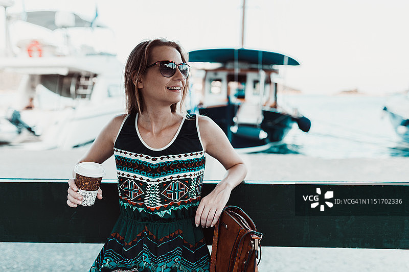 年轻女子在岛上的码头喝咖啡图片素材