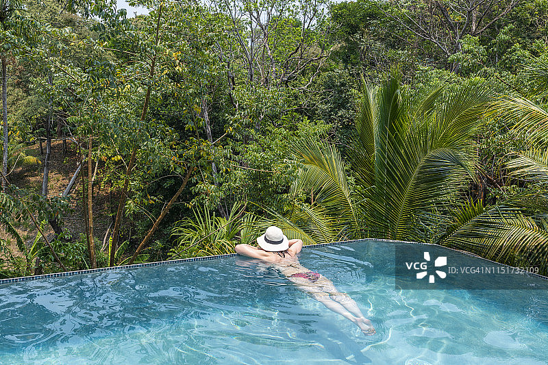 戴白色遮阳帽的女人在森林中享受泳池图片素材