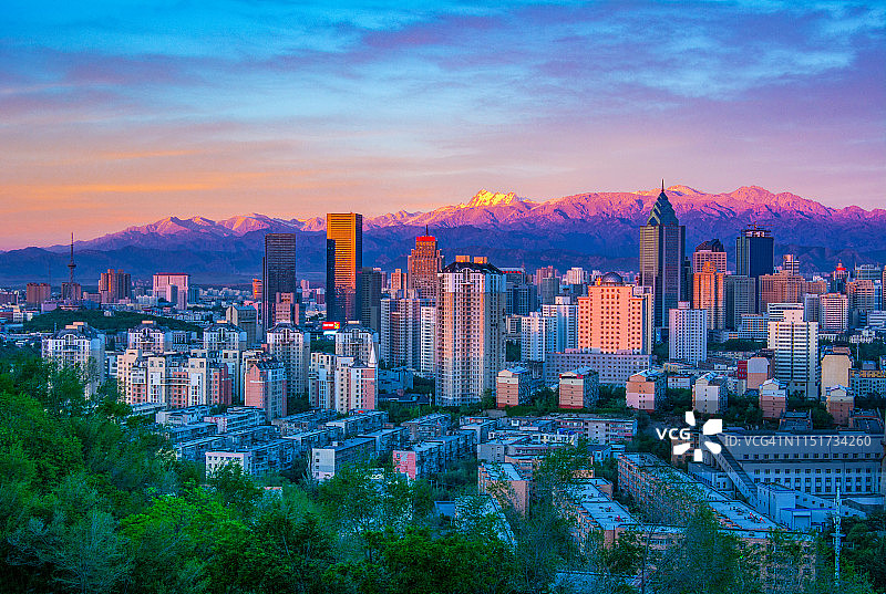 城市建筑与日落下的雪山图片素材