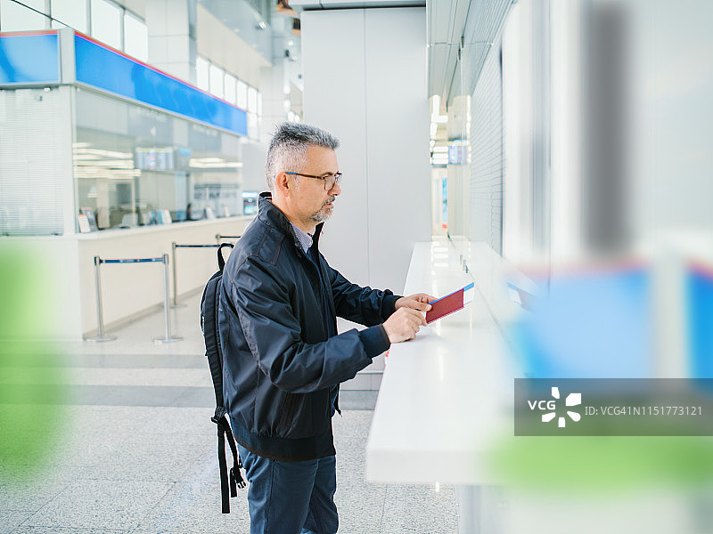 中年男人在机场柜台办理登机手续图片素材