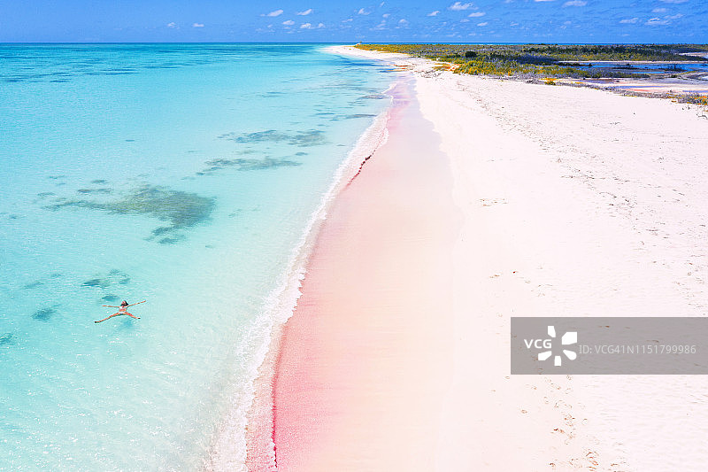 加勒比海巴布达粉色沙滩碧绿海水中漂浮的女子航拍图片素材