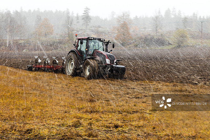 雨中拖拉机耕地图片素材