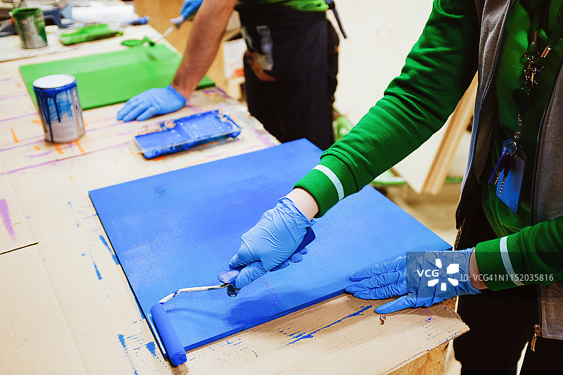 油漆工人在木板上刷漆，进行房屋维修和建筑工作图片素材