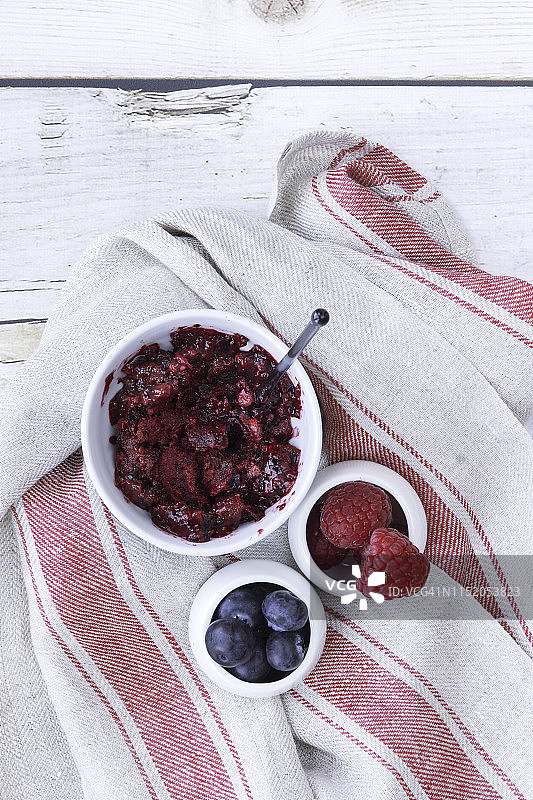 木制桌面上的野生浆果冰淇淋，配新鲜野生浆果和条纹餐巾图片素材