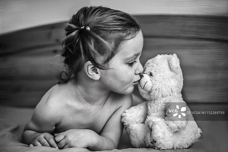 小女孩亲吻她的泰迪熊玩具图片素材