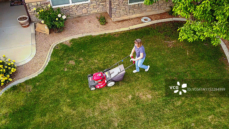 中年妇女在仲春时节用无人机拍摄的草坪修剪视频图片素材