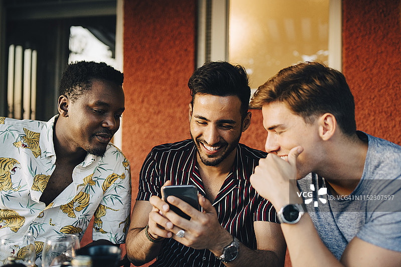 快乐的男人们坐在后院里使用智能手机图片素材
