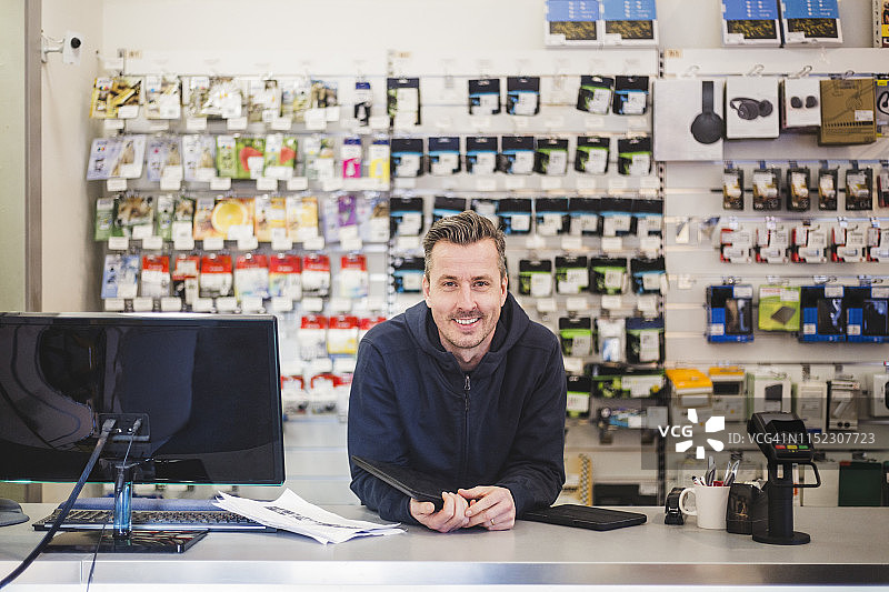 电脑商店里自信微笑的企业家肖像图片素材