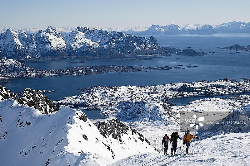 滑雪登山者攀登挪威海后面的Rundfjellet山图片素材