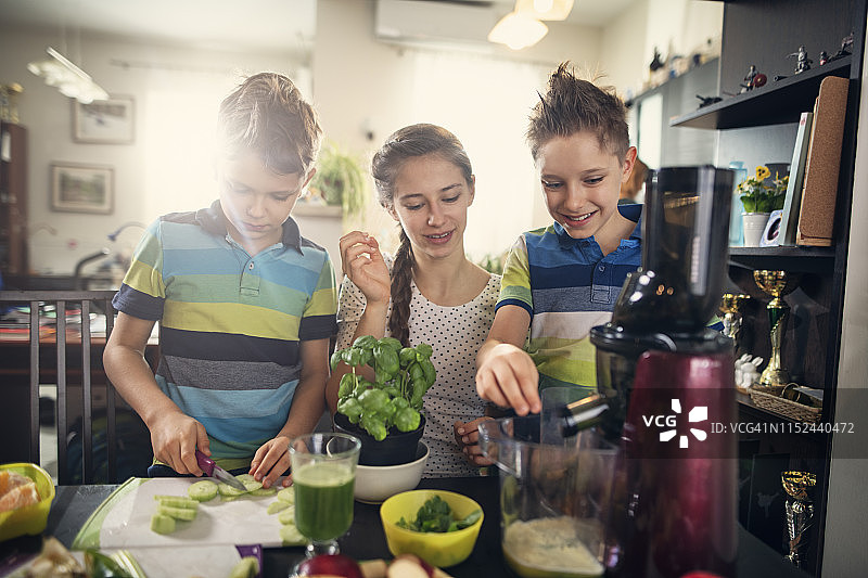 孩子们快乐地用蔬菜水果制作健康果汁图片素材