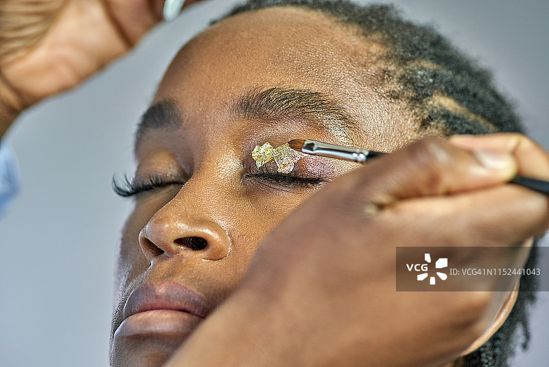 化妆师为年轻女性涂抹金箔眼影图片素材