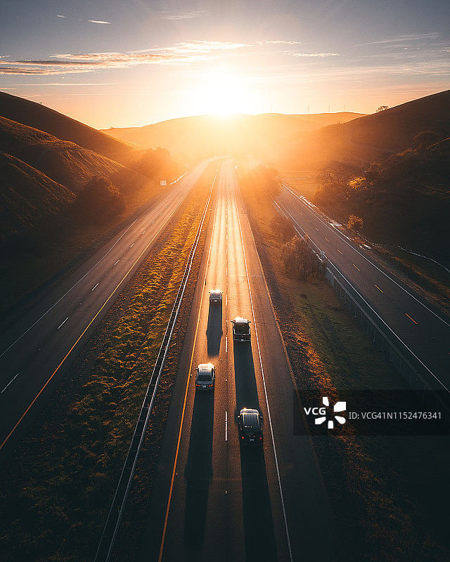 金色光芒照亮偏远公路上的四辆汽车图片素材
