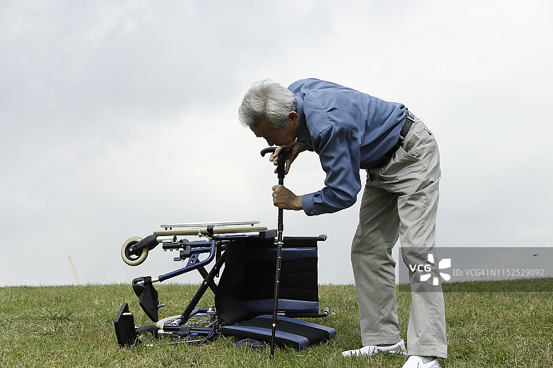 年长的男人拄着拐杖站在草地上图片素材