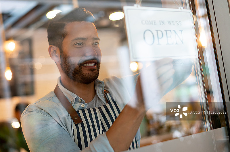 经理在餐厅门上挂营业牌图片素材