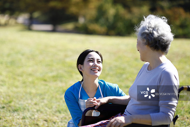护理人员与坐轮椅的老年妇女交谈图片素材