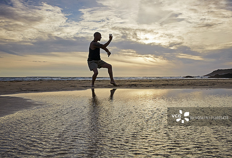 在海滩日落时练习功夫的男人轮廓图片素材