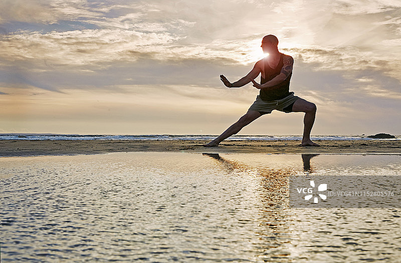 海滩上练习功夫的男人剪影，镜头光晕图片素材