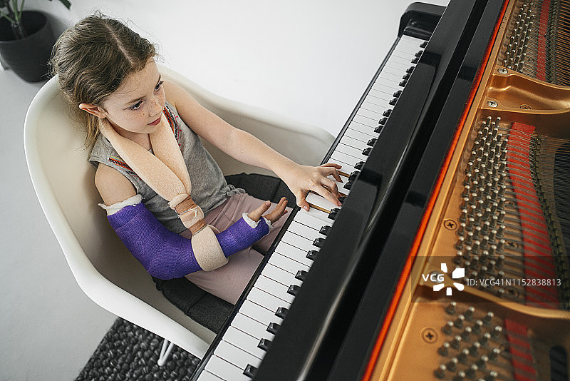 手臂受伤弹钢琴的年轻女孩图片素材