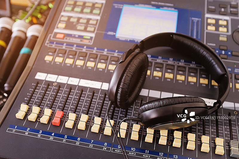 耳机、麦克风、放大设备、工作室音频调音台旋钮和推子、背景调音台。工作场所和设备音响工程师。声音音响音乐混合，选择性聚焦图片素材