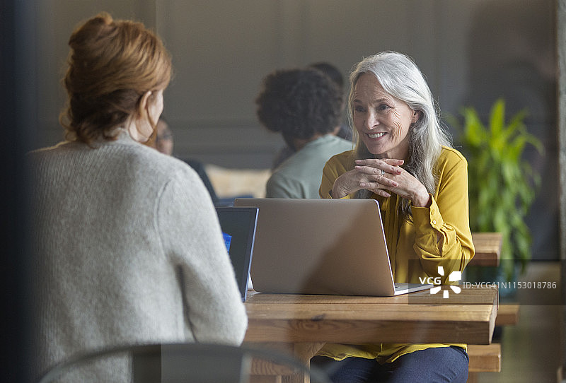 在现代开放式办公室使用笔记本电脑的商务女性图片素材