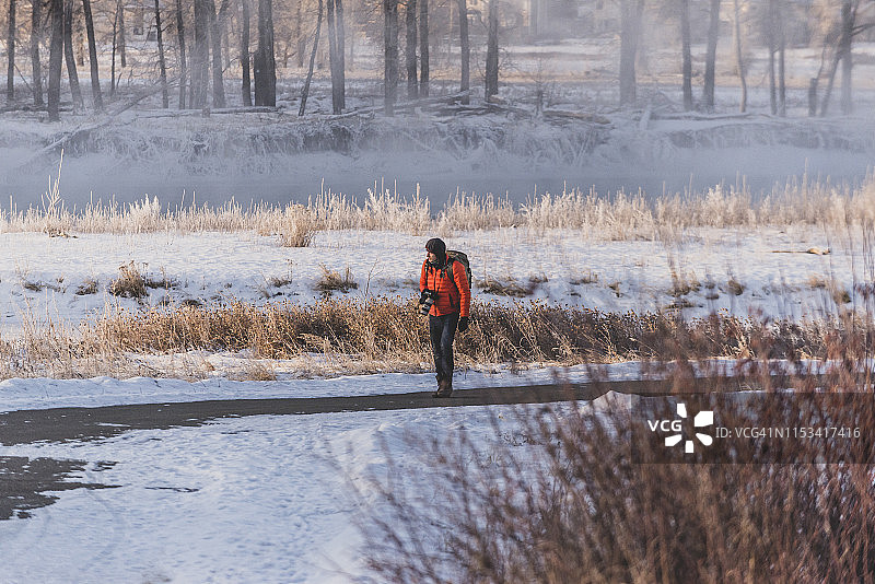 摄影师在卡尔加里冰冻河流旁的自行车道上行走图片素材