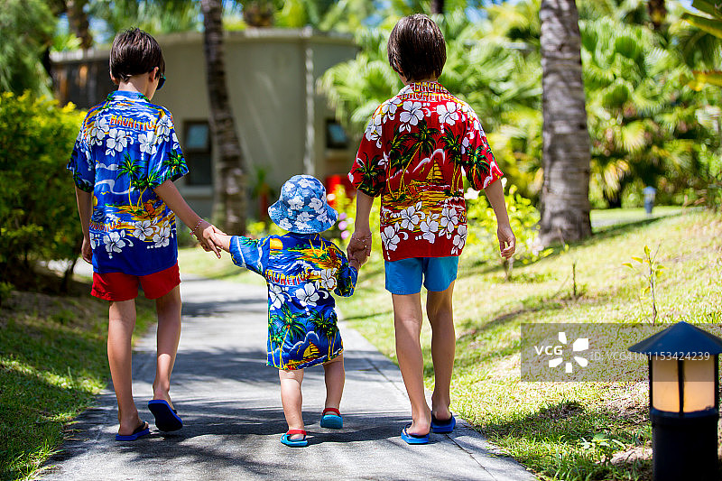 快乐美丽的时尚儿童，穿着夏威夷衬衫，在海滩上一起玩耍，家庭欢乐度假图片素材